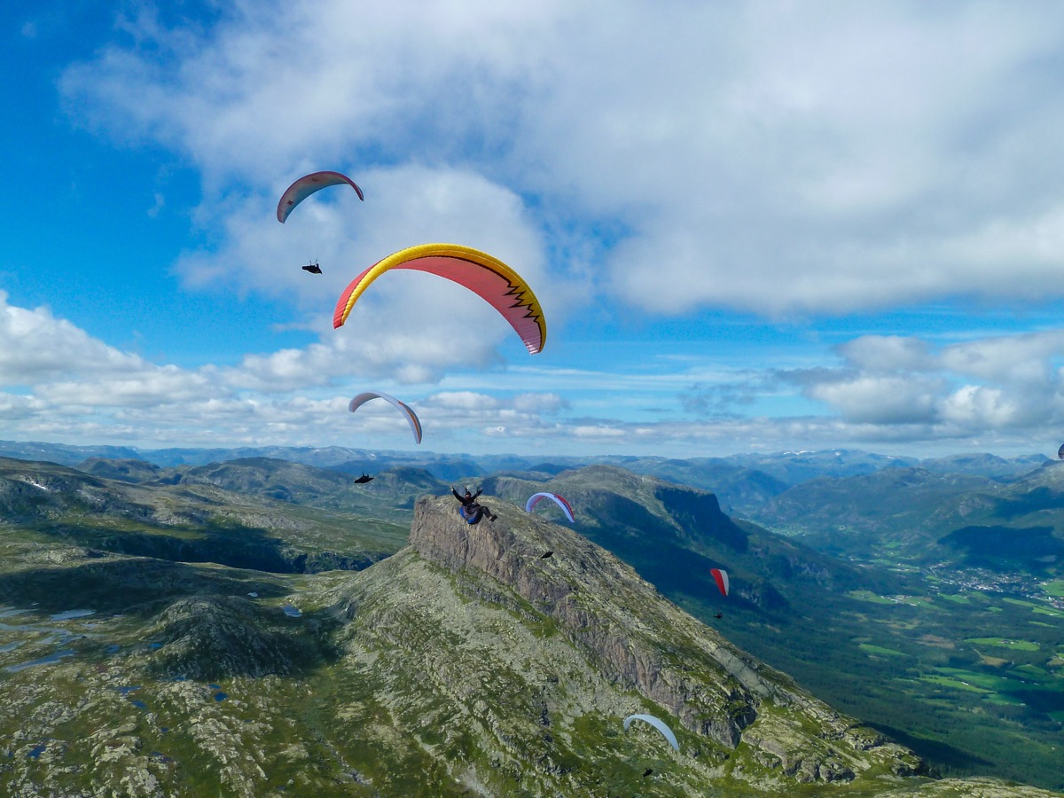 Paraglidere over fjellrygg i Hallingdal med Liagardane i forgrunnen