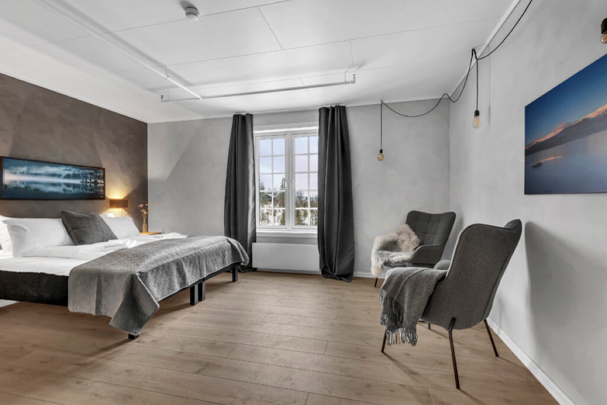 Romslig soverom med dobbeltseng, sittegruppe og kunst på veggen