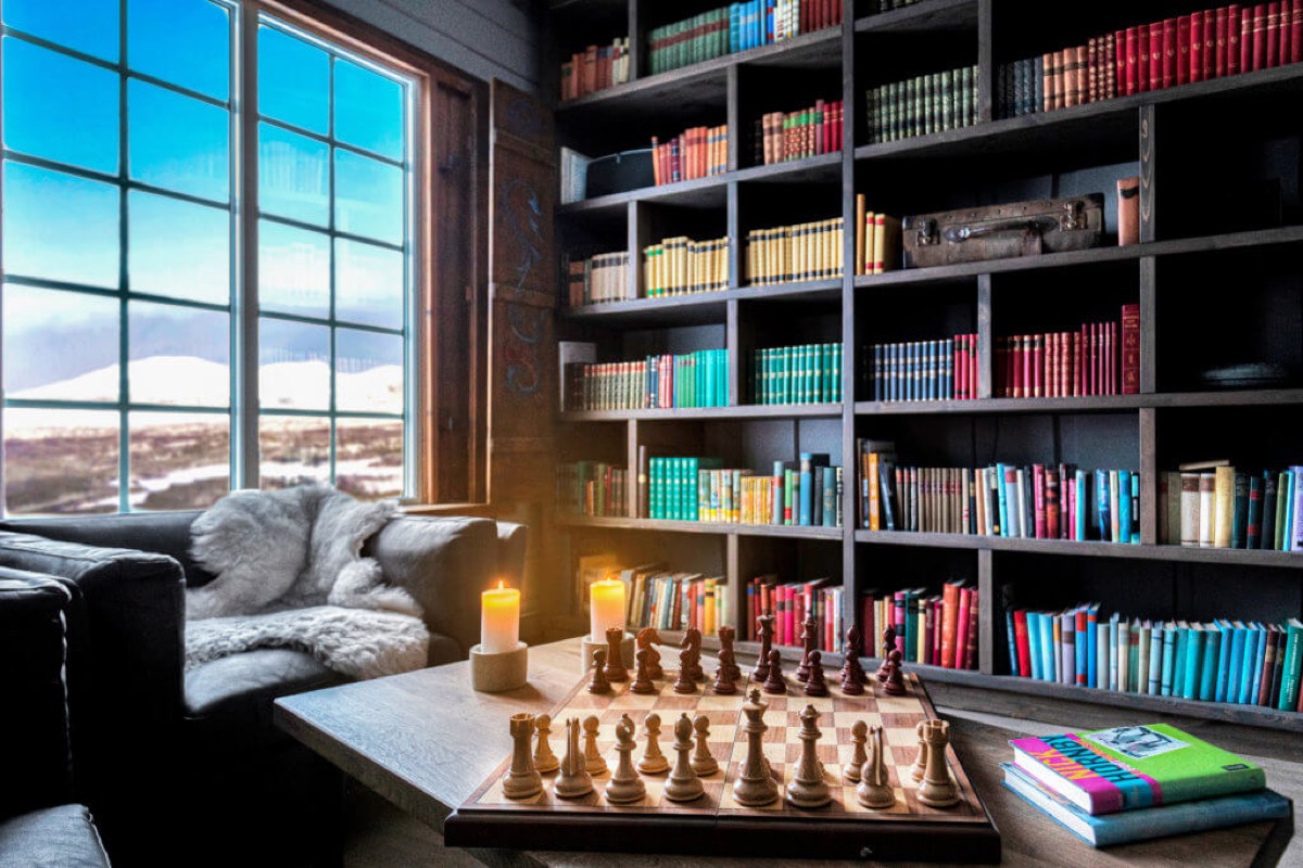 Bibliotek med sjakkbrett og bokhyller mot fjellutsikt
